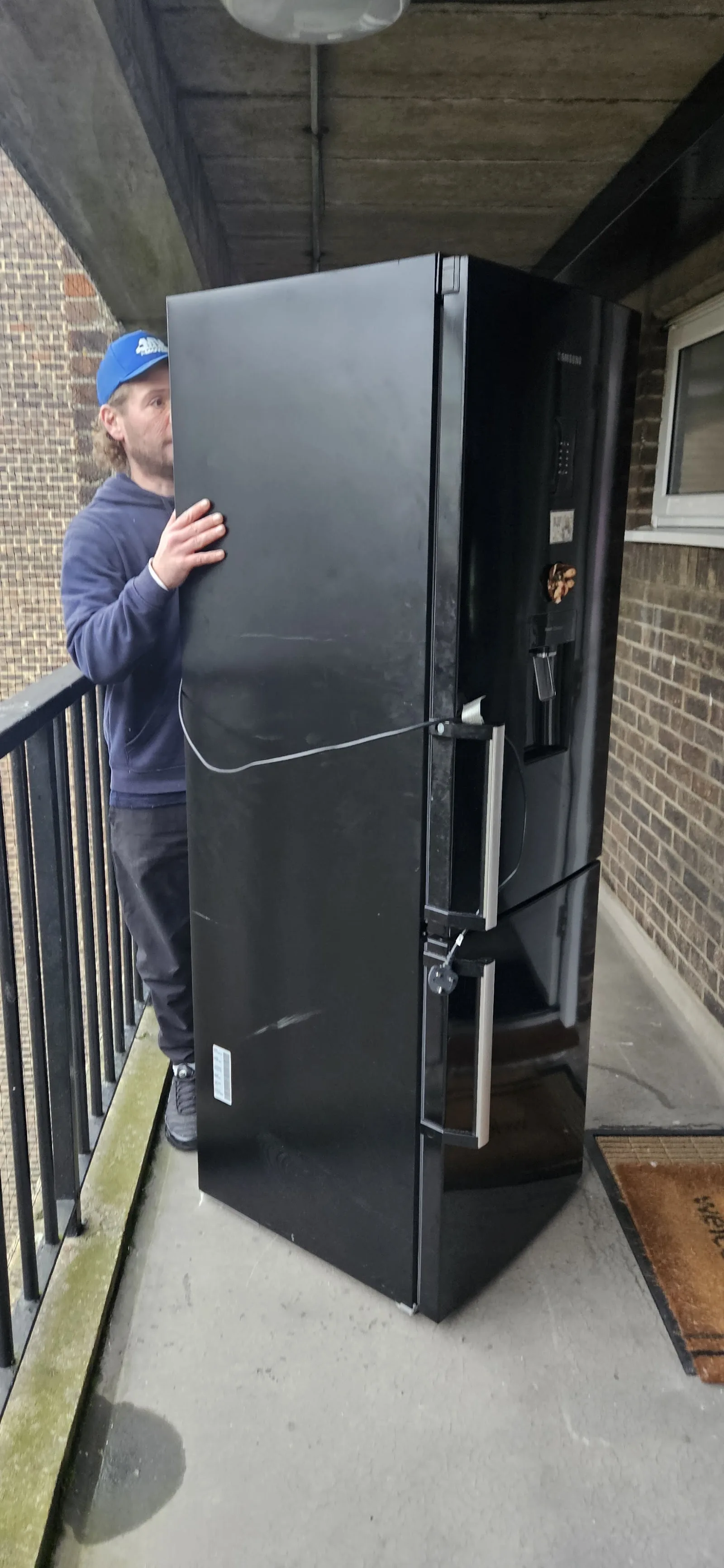 MV Movers carrying a large fridge on a narrow exterior staircase